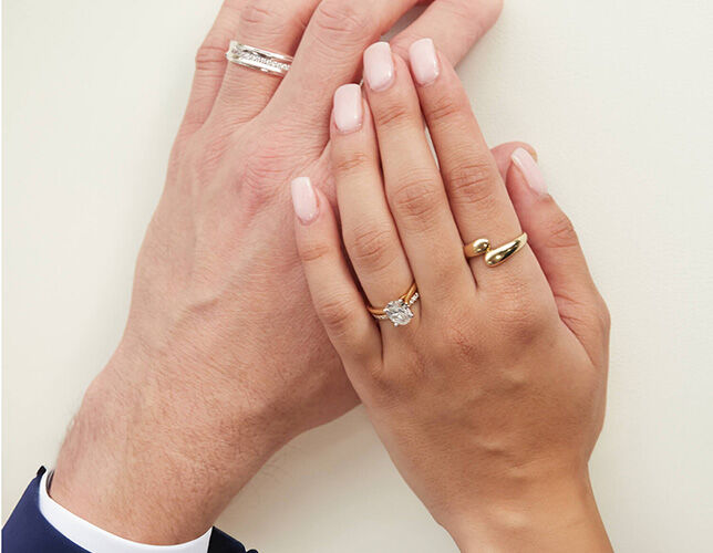 Couple&rsquo;s hands wearing coordinating engagement and wedding rings in yellow and white gold